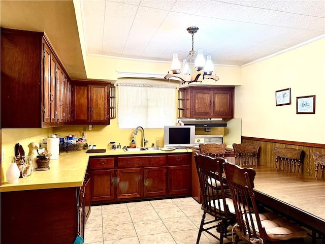 3754 Roman St, Metairie, LA 70001 - kitchen with a sink, a chandelier, light countertops, reddish brown cabinets, and pendant lighting