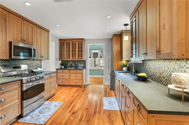 918 Harmony St, New Orleans, LA 70115 - kitchen featuring stainless steel appliances, a sink, dark countertops, backsplash, and light wood finished floors