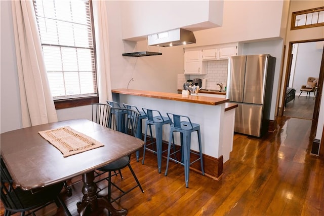 1438-40 Marais St, New Orleans, LA 70116 - kitchen featuring freestanding refrigerator, butcher block counters, decorative backsplash, dark wood-style flooring, and white cabinets