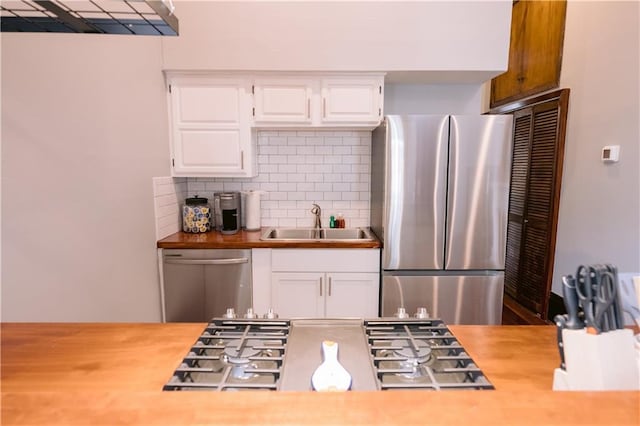 1438-40 Marais St, New Orleans, LA 70116 - kitchen with appliances with stainless steel finishes, a sink, decorative backsplash, and white cabinets