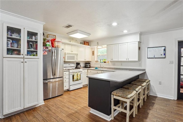 611 Dale Dr, Slidell, LA 70458 - kitchen featuring white appliances, a peninsula, a sink, crown molding, and a kitchen breakfast bar
