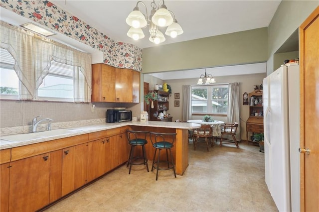 11 Gelbke Dr, Gretna, LA 70053 - kitchen featuring a chandelier, a sink, freestanding refrigerator, light countertops, and brown cabinetry