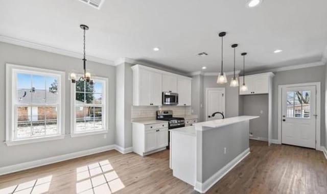 220 Trudeau Dr, Metairie, LA 70003 - kitchen featuring stainless steel appliances, ornamental molding, white cabinetry, light countertops, and light wood finished floors