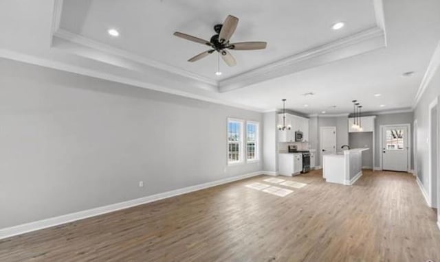 220 Trudeau Dr, Metairie, LA 70003 - unfurnished living room featuring a tray ceiling, ornamental molding, healthy amount of natural light, recessed lighting, and light wood-style floors