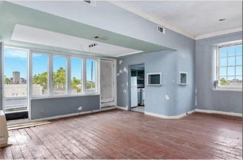 908-10 Esplanade Ave, New Orleans, LA 70116 - unfurnished living room with wood-type flooring, ornamental molding, and baseboards