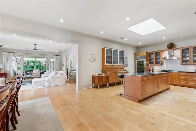 109 Northline St, Metairie, LA 70005 - kitchen with built in fridge, wall chimney range hood, crown molding, an island with sink, and decorative backsplash