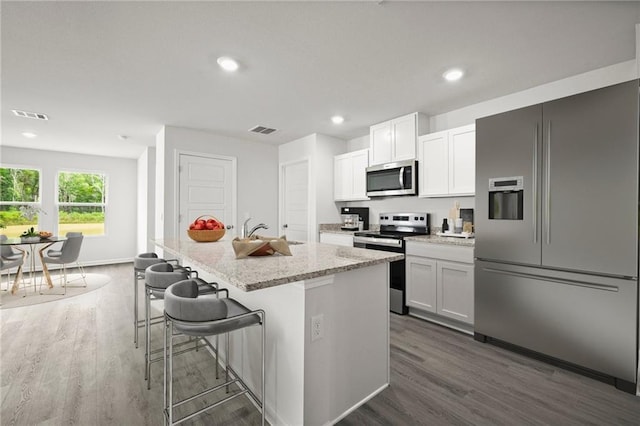 5349 Bypass Breeze Dr, Slidell, LA 70461 - kitchen with appliances with stainless steel finishes, dark wood-style floors, a center island with sink, light stone counters, and recessed lighting