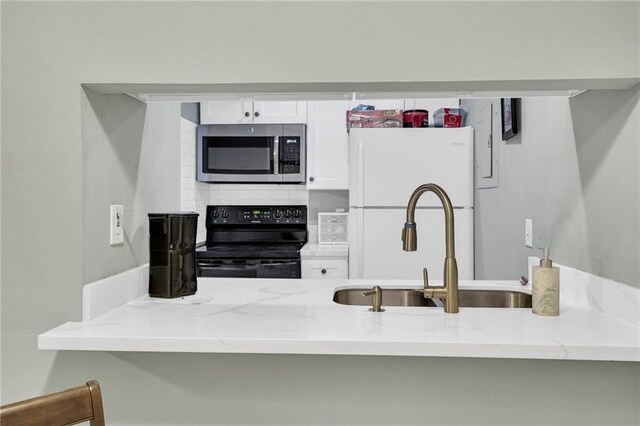 4101 Hessmer Ave Unit 109, Metairie, LA 70002 - kitchen featuring stainless steel microwave, black range with electric stovetop, light stone counters, and freestanding refrigerator