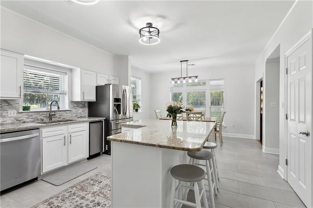 126 Rue Acadian, Belle Chasse, LA 70037 - kitchen with stainless steel appliances, a sink, a kitchen breakfast bar, decorative backsplash, and a center island