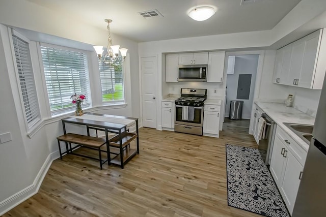 1414 Englewood Dr, Slidell, LA 70458 - kitchen featuring appliances with stainless steel finishes, light wood-style flooring, a chandelier, and white cabinets