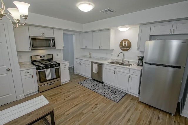 1414 Englewood Dr, Slidell, LA 70458 - kitchen featuring stainless steel appliances, a sink, light countertops, light wood-style floors, and white cabinetry