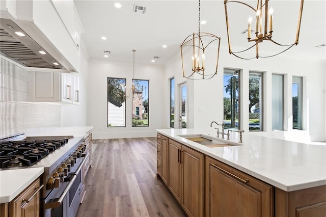 1001 Helios Ave, Metairie, LA 70005 - kitchen featuring custom range hood, a sink, a chandelier, range with two ovens, and a large island