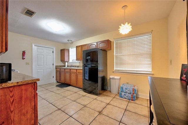 7701 Allison Rd, New Orleans, LA 70126 - kitchen featuring freestanding refrigerator, light tile patterned flooring, light countertops, and brown cabinetry