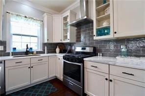 324 N Roman St, New Orleans, LA 70112 - kitchen with stainless steel gas stove, wall chimney range hood, light countertops, a sink, and crown molding