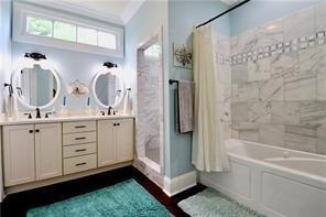 324 N Roman St, New Orleans, LA 70112 - full bath with double vanity, shower / bathtub combination with curtain, baseboards, crown molding, and wood finished floors