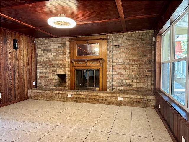 570 Central Ave, Reserve, LA 70084 - unfurnished living room with wood ceiling with exposed beams, wooden walls, a brick fireplace, brick wall, and light tile patterned floors