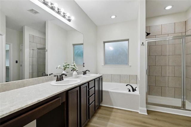 130 Palm Beach Blvd, Madisonville, LA 70447 - bathroom featuring double vanity, a shower stall, a garden tub, and wood finished floors