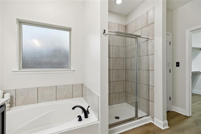 130 Palm Beach Blvd, Madisonville, LA 70447 - bathroom featuring a bath, a stall shower, a walk in closet, wood finished floors, and baseboards