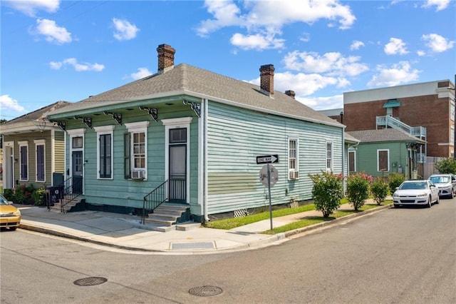 1432-1434 Ursulines Ave, New Orleans, LA 70116 - view of side of property with entry steps, a chimney, cooling unit, and roof with shingles