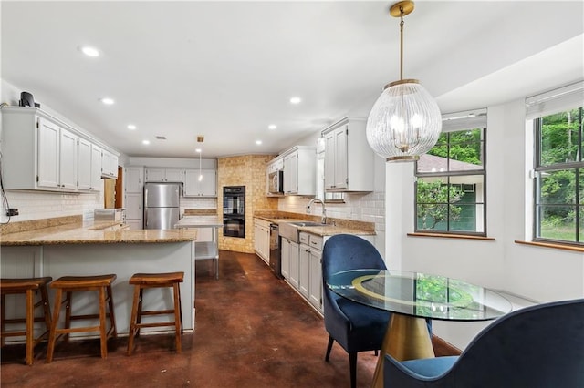 505 Hermitage Ct, Pearl River, LA 70452 - kitchen with stainless steel appliances, concrete flooring, a peninsula, tasteful backsplash, and light stone countertops