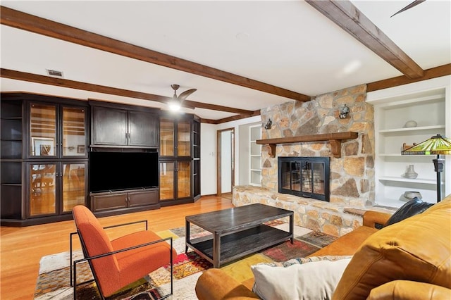 505 Hermitage Ct, Pearl River, LA 70452 - living area featuring light wood-style flooring, beamed ceiling, a stone fireplace, built in shelves, and a ceiling fan