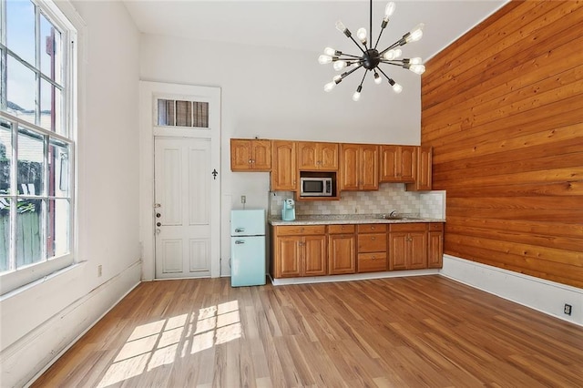 1314 Ursulines Ave, New Orleans, LA 70116 - kitchen with stainless steel microwave, freestanding refrigerator, a chandelier, brown cabinets, and light countertops
