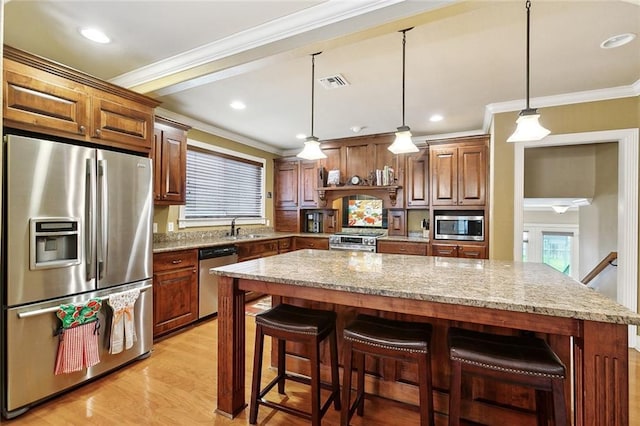 5878 General Diaz St, New Orleans, LA 70124 - kitchen featuring appliances with stainless steel finishes, a sink, ornamental molding, light stone counters, and a kitchen island