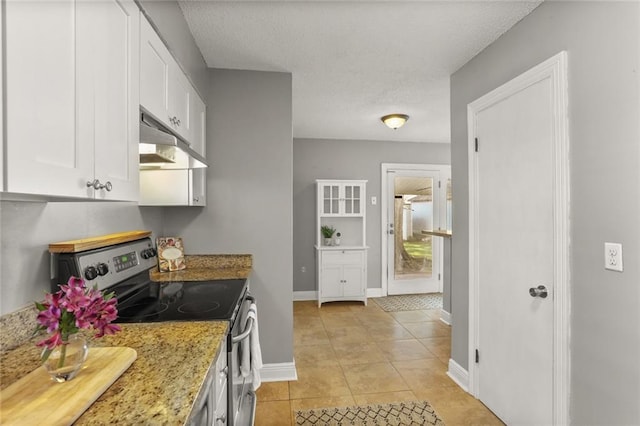 6020 Loraine St, Metairie, LA 70003 - kitchen with stainless steel electric range, under cabinet range hood, white cabinetry, light tile patterned floors, and baseboards