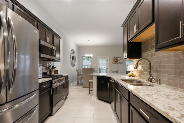 11537 Woodbluff Dr, Covington, LA 70433 - kitchen featuring stainless steel appliances, a sink, decorative backsplash, light stone countertops, and light tile patterned flooring