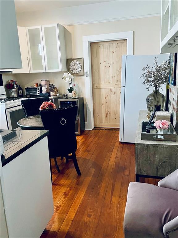 905-907 Pelican Ave, New Orleans, LA 70114 - kitchen with white appliances, dark wood-style flooring, white cabinetry, exhaust hood, and tile countertops