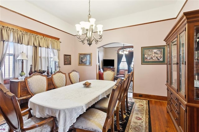 115 N Scott St, New Orleans, LA 70119 - dining area featuring arched walkways, a chandelier, baseboards, and hardwood / wood-style flooring