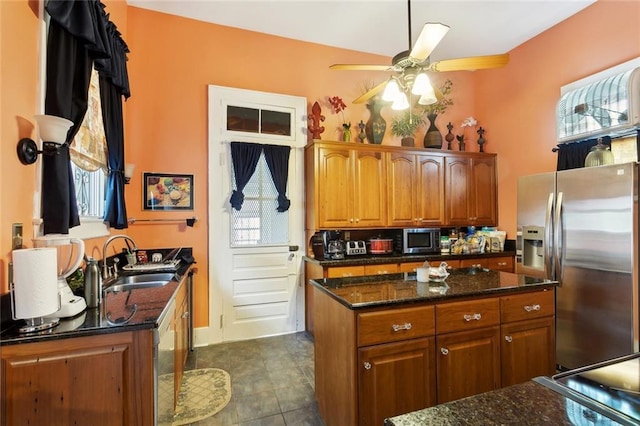 115 N Scott St, New Orleans, LA 70119 - kitchen featuring a sink, stainless steel appliances, ceiling fan, brown cabinets, and dark stone countertops