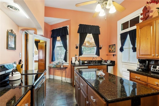 115 N Scott St, New Orleans, LA 70119 - kitchen featuring electric range, a sink, ceiling fan, arched walkways, and dark stone counters