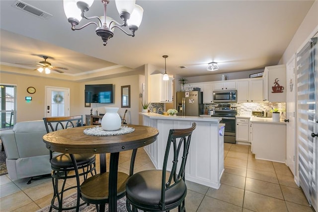 28272 Lake Salvador Dr, Livingston, LA 70754 - dining area featuring light tile patterned flooring, a chandelier, a raised ceiling, and ceiling fan