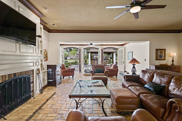 553 Beau Chene Dr, Mandeville, LA 70471 - living room featuring a ceiling fan, crown molding, a brick fireplace, brick floors, and a textured ceiling