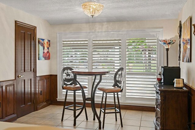 553 Beau Chene Dr, Mandeville, LA 70471 - dining space featuring a textured ceiling, light tile patterned floors, and wainscoting