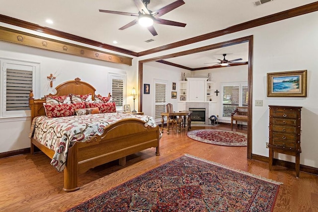 553 Beau Chene Dr, Mandeville, LA 70471 - bedroom with crown molding, wood finished floors, and a tiled fireplace