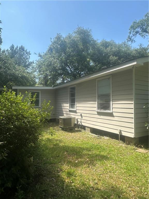 25594 W Spruce St, Lacombe, LA 70445 - rear view of property with central AC unit and a lawn