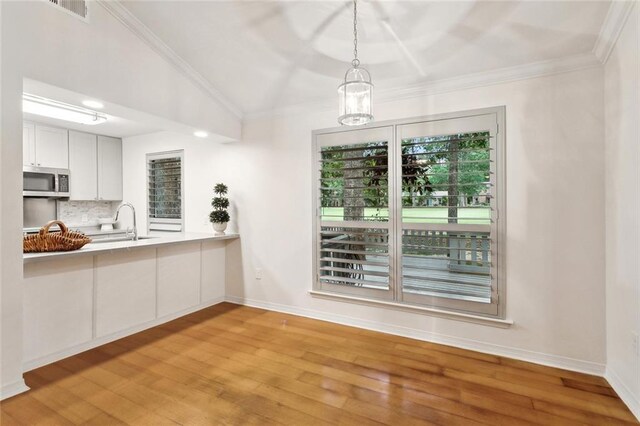 640 Tete Lours Dr Unit 28, Mandeville, LA 70471 - unfurnished dining area featuring light wood-type flooring, a sink, baseboards, crown molding, and vaulted ceiling