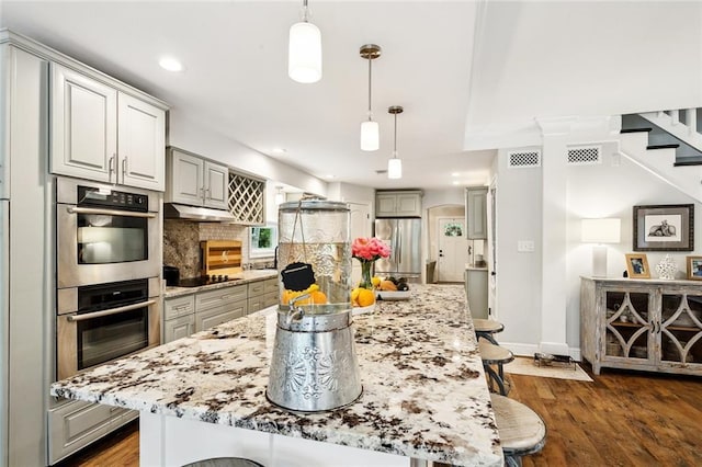27044 Lucille Dr, Lacombe, LA 70445 - kitchen with appliances with stainless steel finishes, a breakfast bar area, backsplash, hanging light fixtures, and recessed lighting