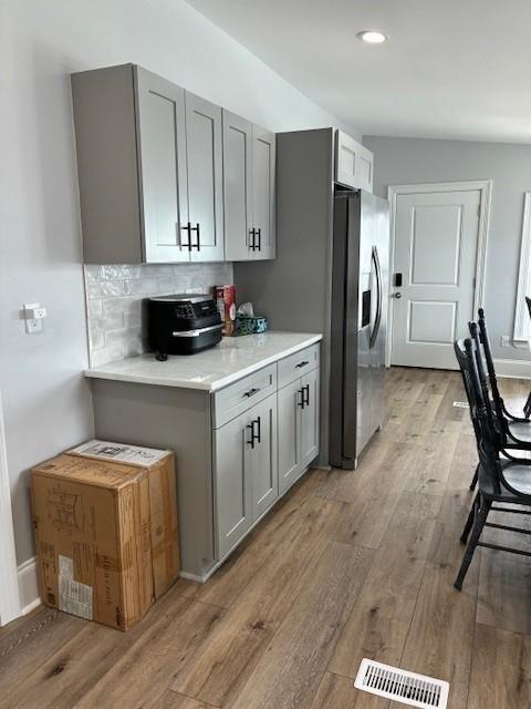131 Verley Ln, Grand Isle, LA 70358 - kitchen with stainless steel refrigerator with ice dispenser, gray cabinetry, light wood-type flooring, light countertops, and recessed lighting