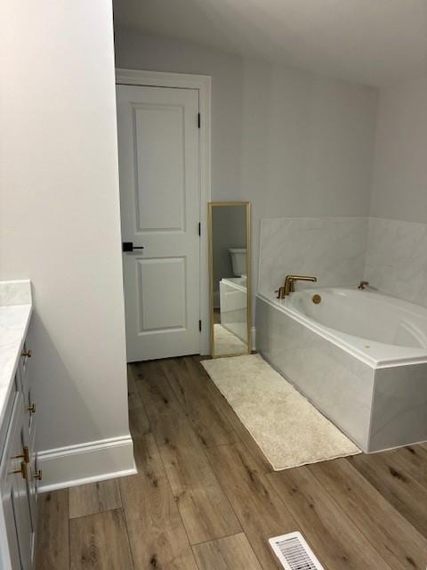 131 Verley Ln, Grand Isle, LA 70358 - full bath with vanity, a bath, wood finished floors, and baseboards
