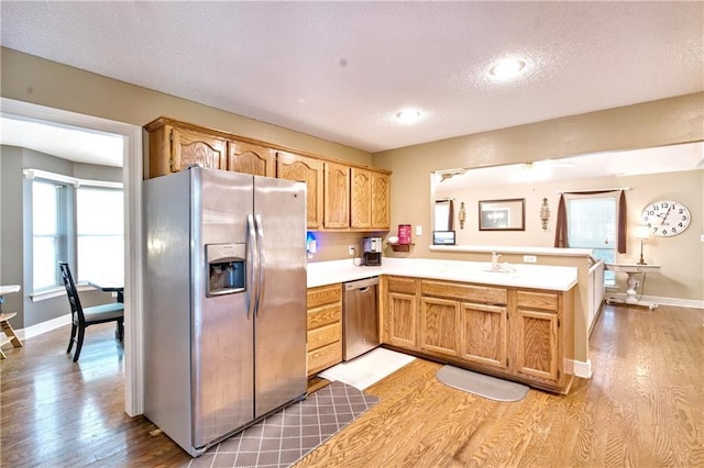 21360 Stire St, Abita Springs, LA 70420 - kitchen featuring appliances with stainless steel finishes, a peninsula, light wood-style flooring, light countertops, and a textured ceiling