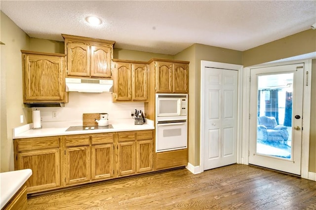 21360 Stire St, Abita Springs, LA 70420 - kitchen with white appliances, under cabinet range hood, light wood finished floors, a textured ceiling, and light countertops