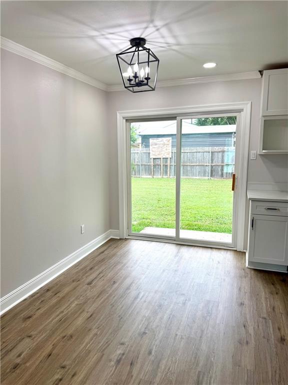 3805 Purdue Dr, Metairie, LA 70003 - unfurnished dining area featuring ornamental molding, dark wood-style floors, baseboards, and a chandelier