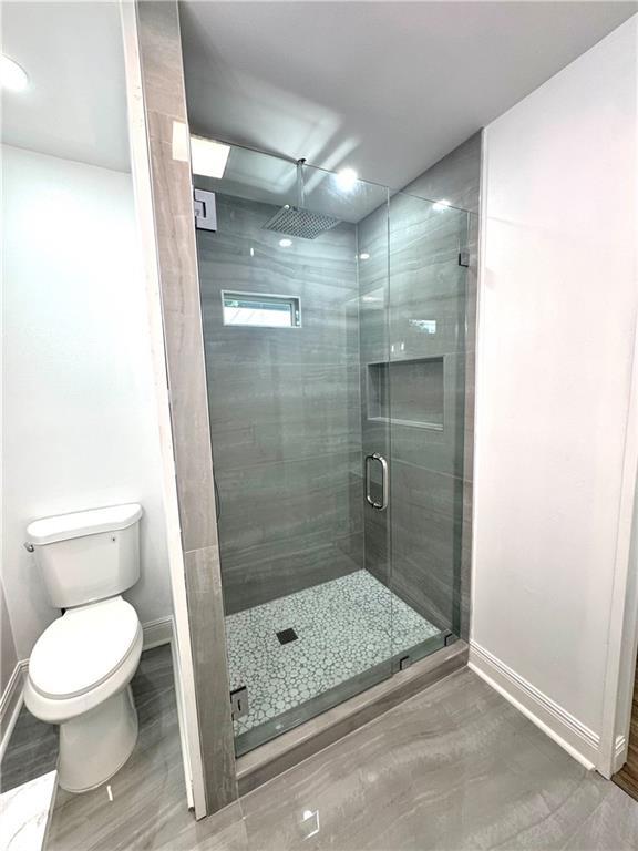 3805 Purdue Dr, Metairie, LA 70003 - full bathroom featuring baseboards, a stall shower, toilet, and wood finished floors
