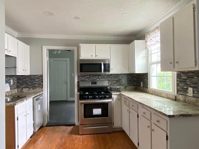7 Labarre Pl, Jefferson, LA 70121 - kitchen with stainless steel appliances, ornamental molding, wood finished floors, tasteful backsplash, and white cabinets