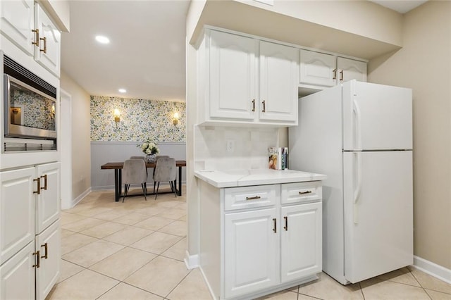 4912 Ithaca St, Metairie, LA 70006 - kitchen featuring freestanding refrigerator, stainless steel microwave, baseboards, light countertops, and white cabinets