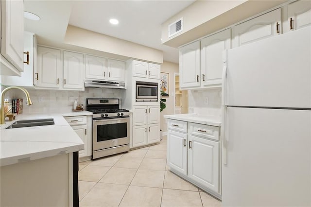 4912 Ithaca St, Metairie, LA 70006 - kitchen with stainless steel appliances, range hood, a sink, white cabinets, and light tile patterned flooring