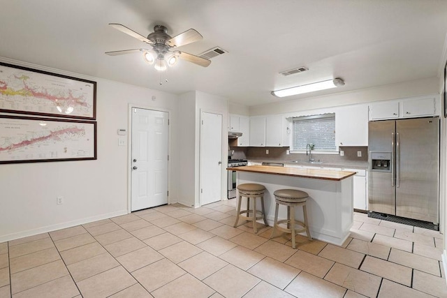 110 Willow Dr, Covington, LA 70433 - kitchen with stainless steel appliances, a sink, white cabinetry, a breakfast bar, and a center island
